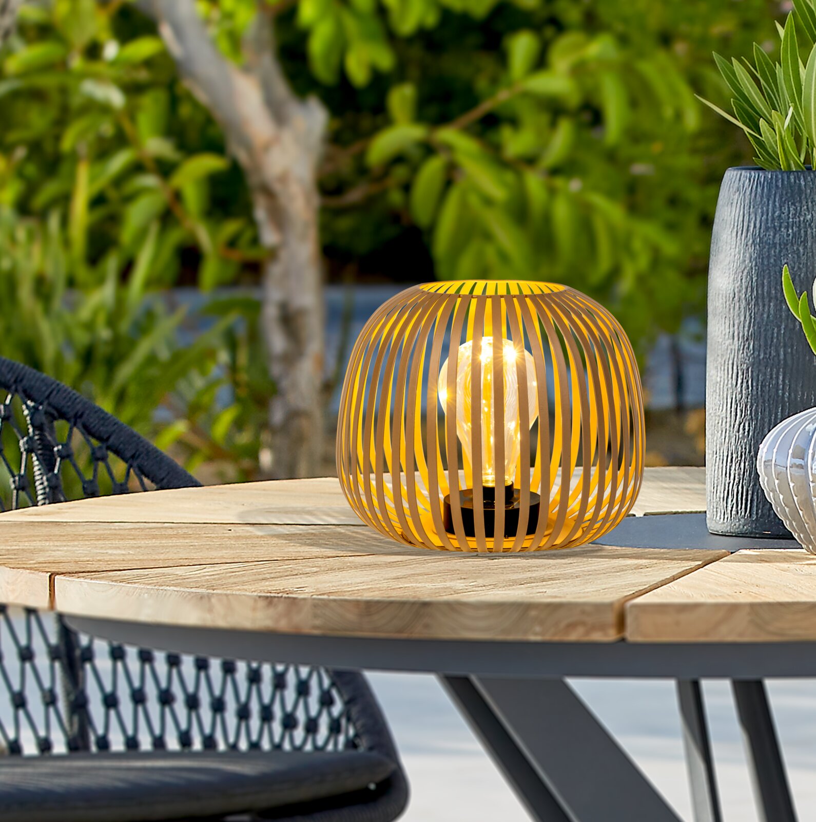 Ambia Garden Solarleuchte GLENDALE Gelbe Solarleuchte in moderner Gitteroptik auf einem Holztisch im Freien, seitliche Perspektive