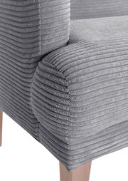 Nahaufnahme eines grauen, gerippten Sofas mit Holzbeinen, Perspektive von der Seite