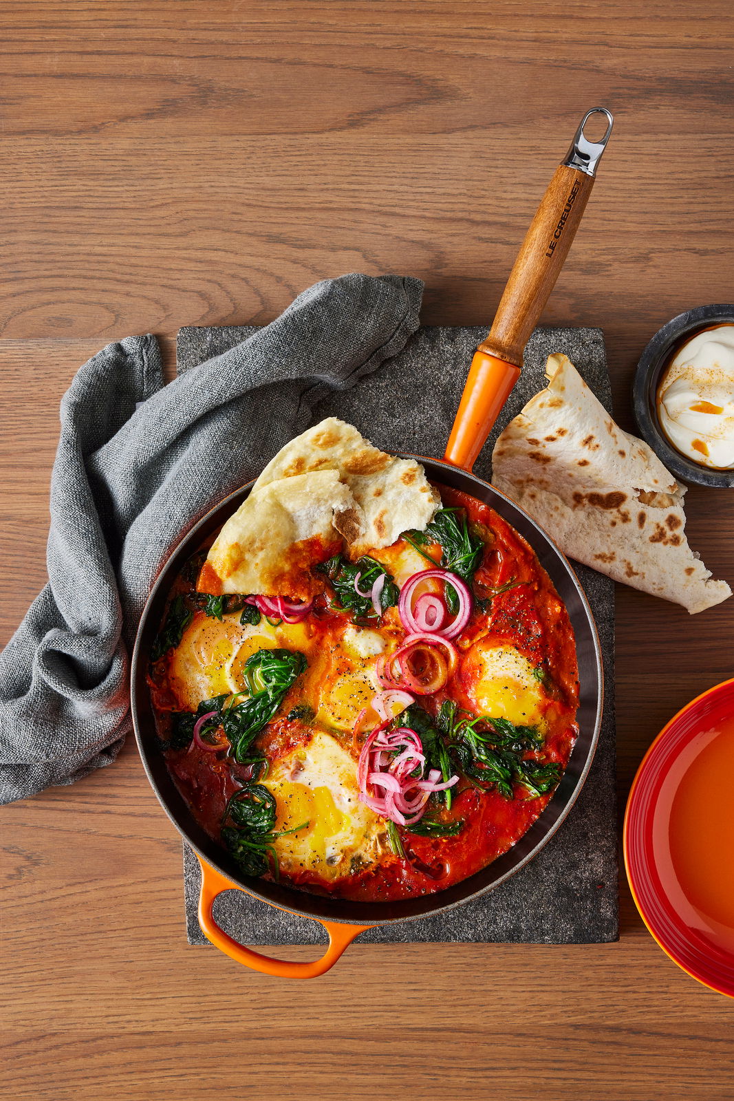 LE CREUSET Sautépfanne 28cm Ofenrot Sautepfanne in Ofenrot mit Holzgriff, gefüllt mit einem bunten Gericht aus Eiern, Spinat und Zwiebeln, von oben fotografiert.