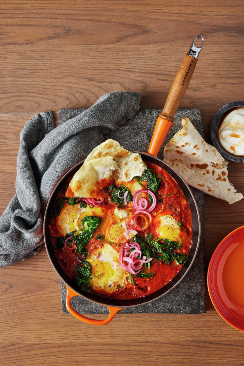 LE CREUSET Sautépfanne 28cm Ofenrot Sautepfanne in Ofenrot mit Holzgriff, gefüllt mit einem bunten Gericht aus Eiern, Spinat und Zwiebeln, von oben fotografiert.