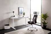 Moderner E-Schreibtisch in einem hellen Raum, seitliche Perspektive, mit ergonomischem Bürostuhl und Dekoration.