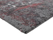 Nahaufnahme eines modernen Teppichs in Grau- und Rottönen mit strukturierter Oberfläche, perspektivisch von der Seite aufgenommen.