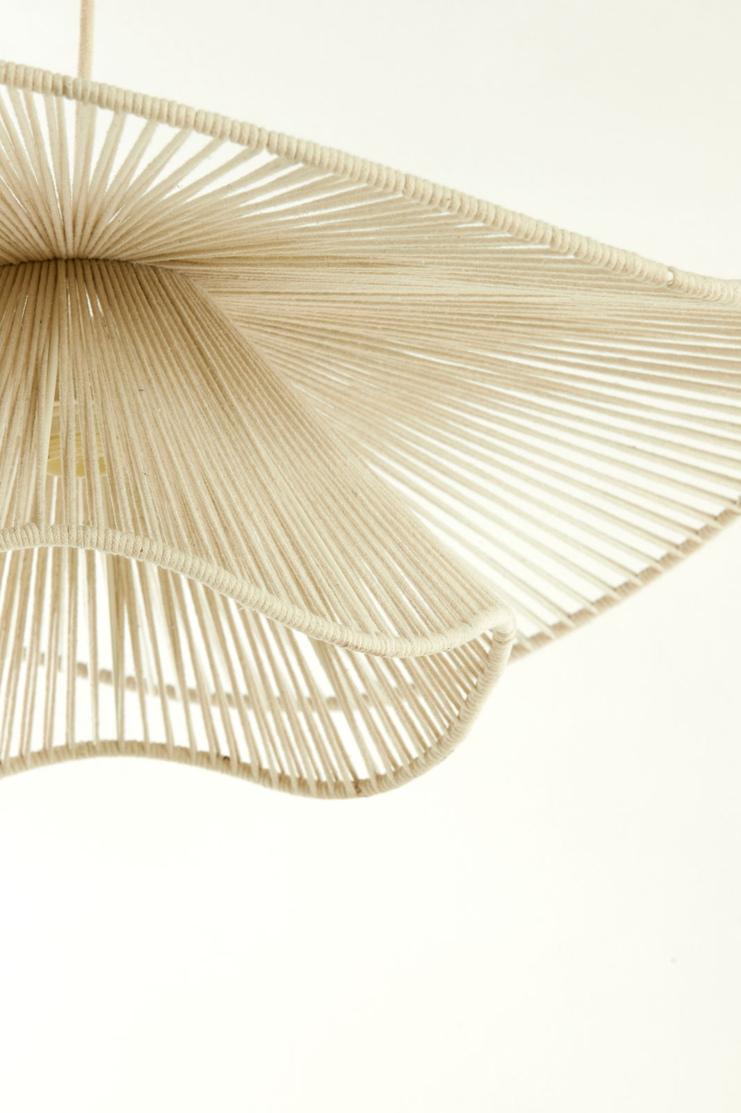 Nahaufnahme einer Hängeleuchte mit einem eleganten, gewellten Design aus beigem Seilmaterial, von unten betrachtet.