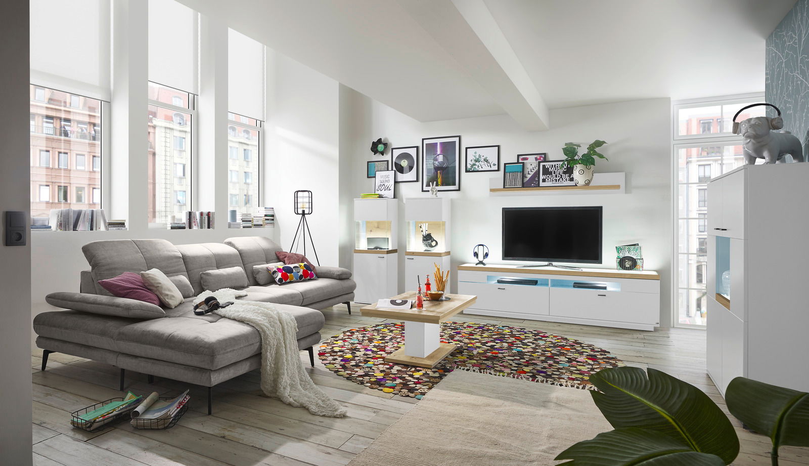 Modernes Wohnzimmer mit grauem Sofa, Couchtisch und TV-Lowboard in heller, stilvoller Einrichtung. Perspektive von der Seite.