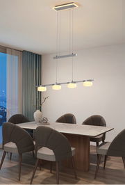 Moderne Pendelleuchte Jesse mit vier leuchtenden Lampenschirmen über einem Esstisch, seitliche Perspektive.