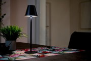 Zwarte accu-tafellamp op een tafel met een kleurrijk tafelkleed, zijaanzicht