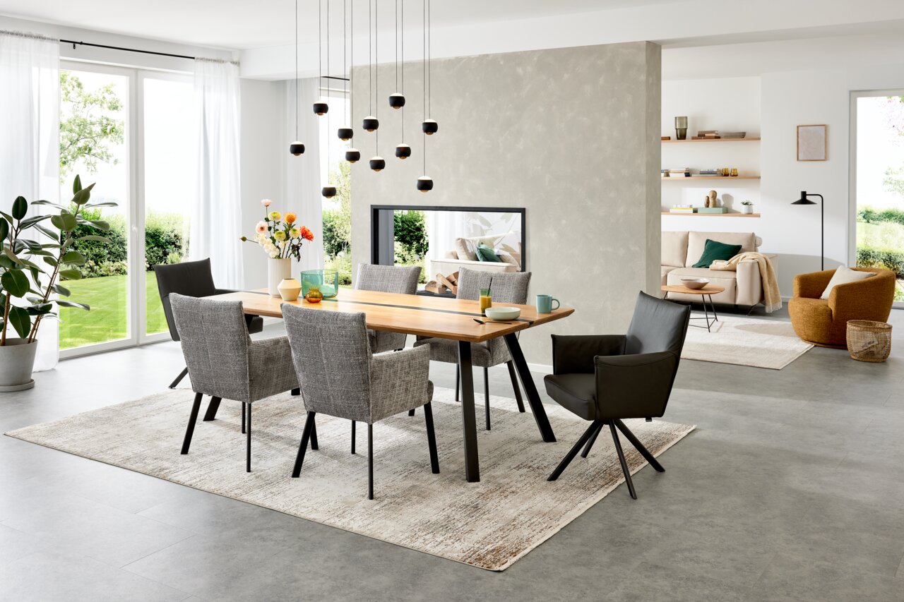 Esszimmer mit großem Holztisch und sechs Armlehnstühlen, moderne Einrichtung, seitliche Perspektive