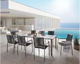 Moderner Gartensessel und Esstisch auf einer Terrasse mit Meerblick, seitliche Perspektive.