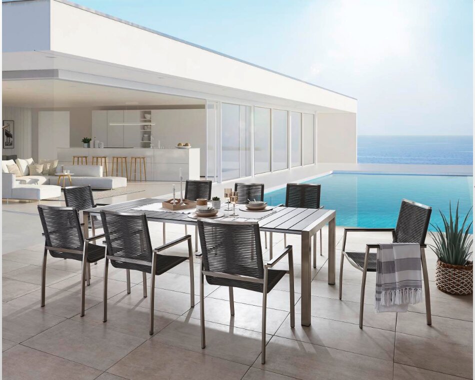 Amatio Gartensessel GIRONA Moderner Gartensessel und Esstisch auf einer Terrasse mit Meerblick, seitliche Perspektive.