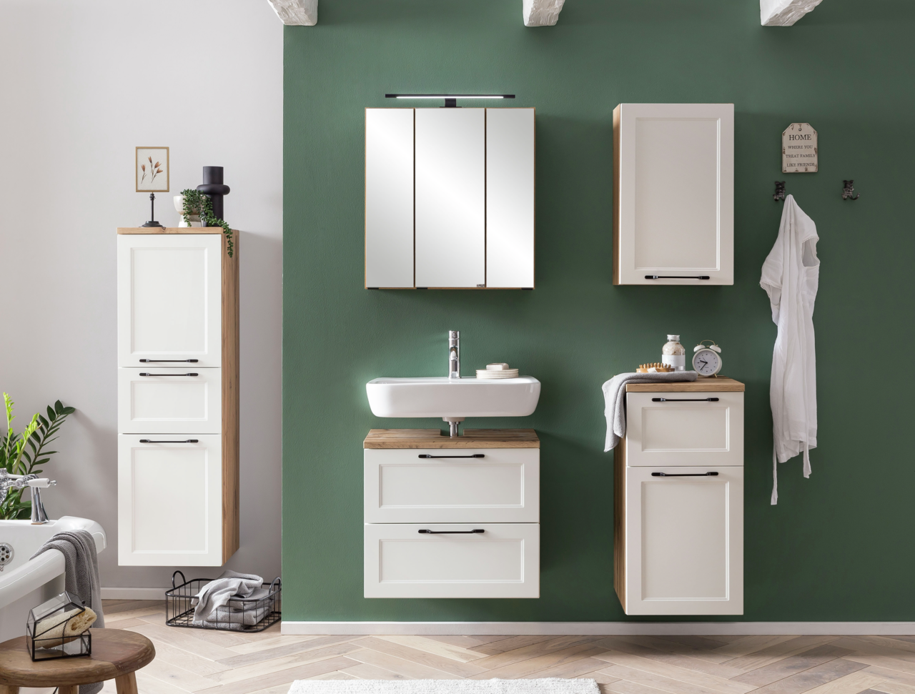 Moderner Waschbeckenunterschrank in einem stilvollen Badezimmer, frontal betrachtet, mit weißer Front und Holzdetails, passend zu anderen Hängeschränken an einer grünen Wand.