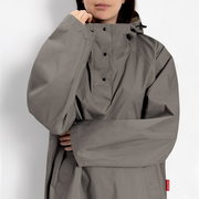 Grauer Regenponcho/Anorak mit hohem Kragen und Druckknopf-Leiste, getragen von einer Person; Frontansicht in Nahaufnahme (Oberkörper)
