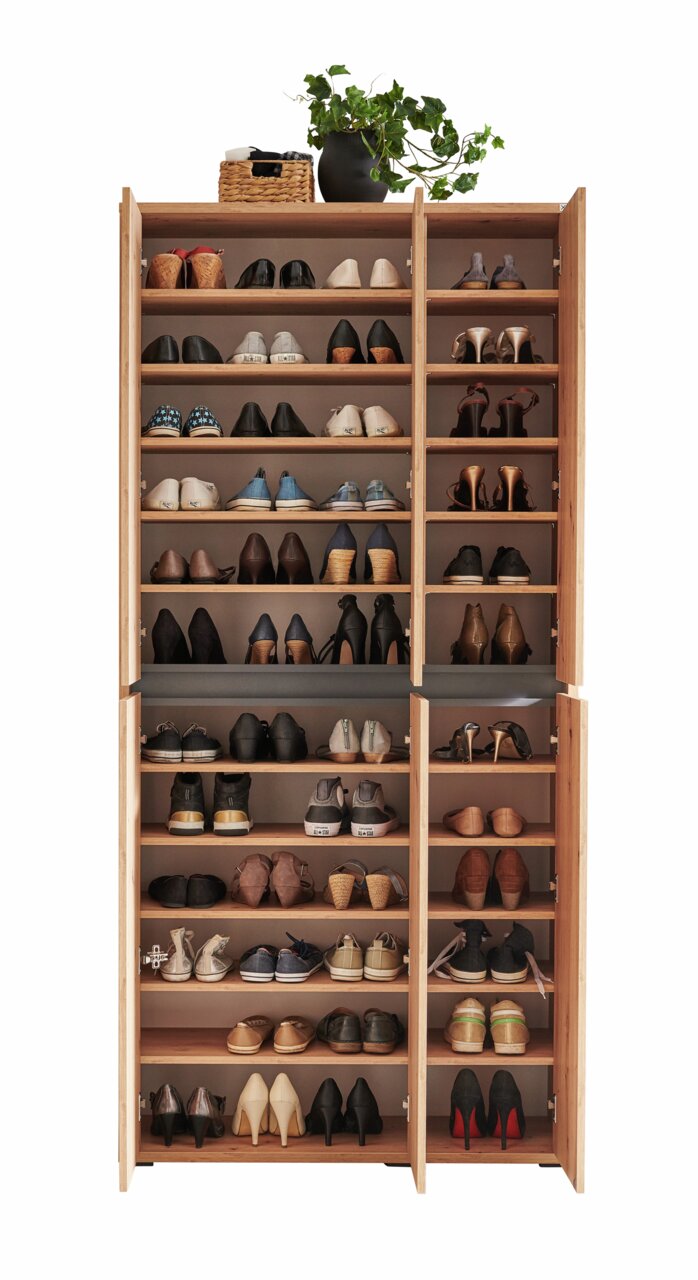Vorderansicht eines XXL-Schuhschranks mit offenen Türen, gefüllt mit verschiedenen Schuhen und dekoriert mit einem Pflanzenarrangement oben.