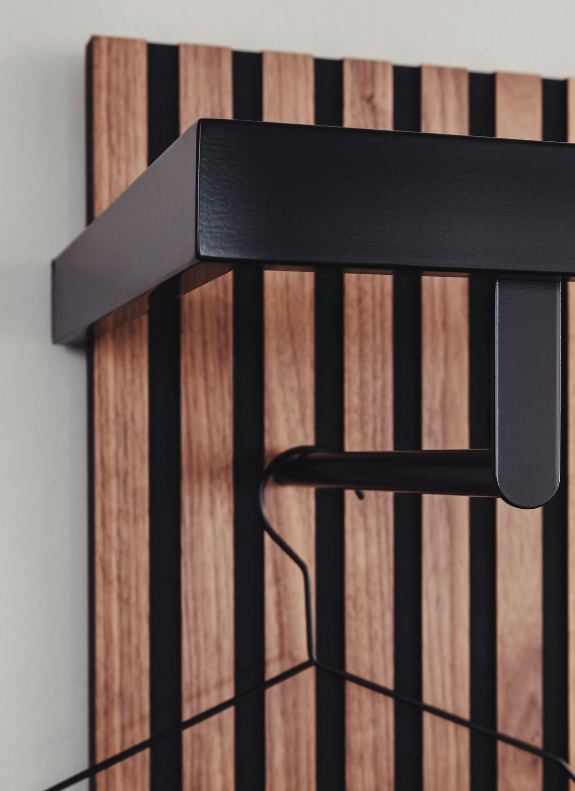 Nahaufnahme eines modernen Garderobenpaneels mit Holz- und Metallelementen, seitliche Perspektive.