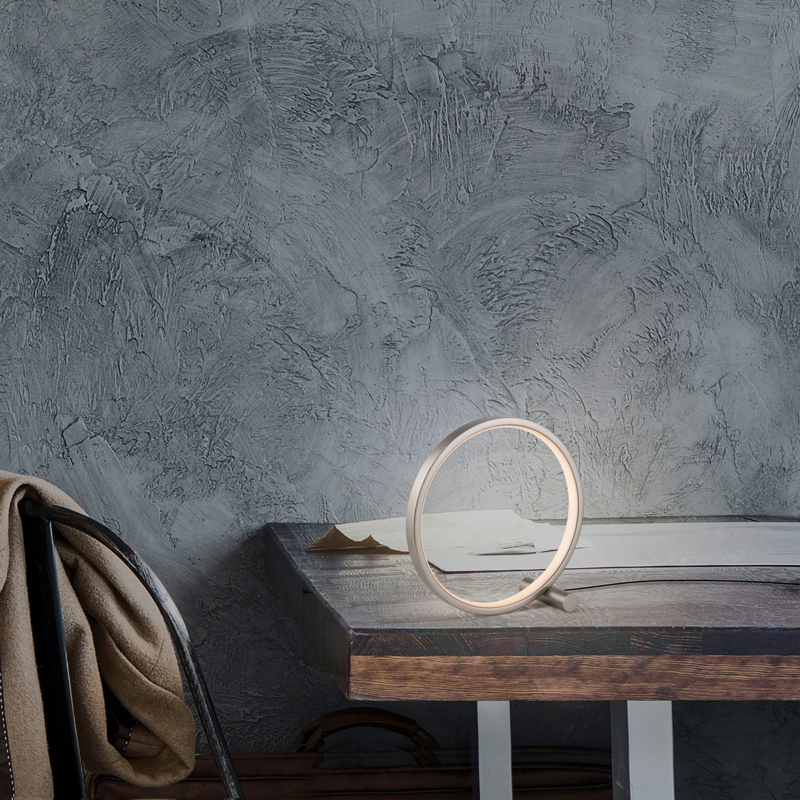 Moderne Tischleuchte MINI RITUS in Ringform auf einem Holztisch, seitliche Perspektive.