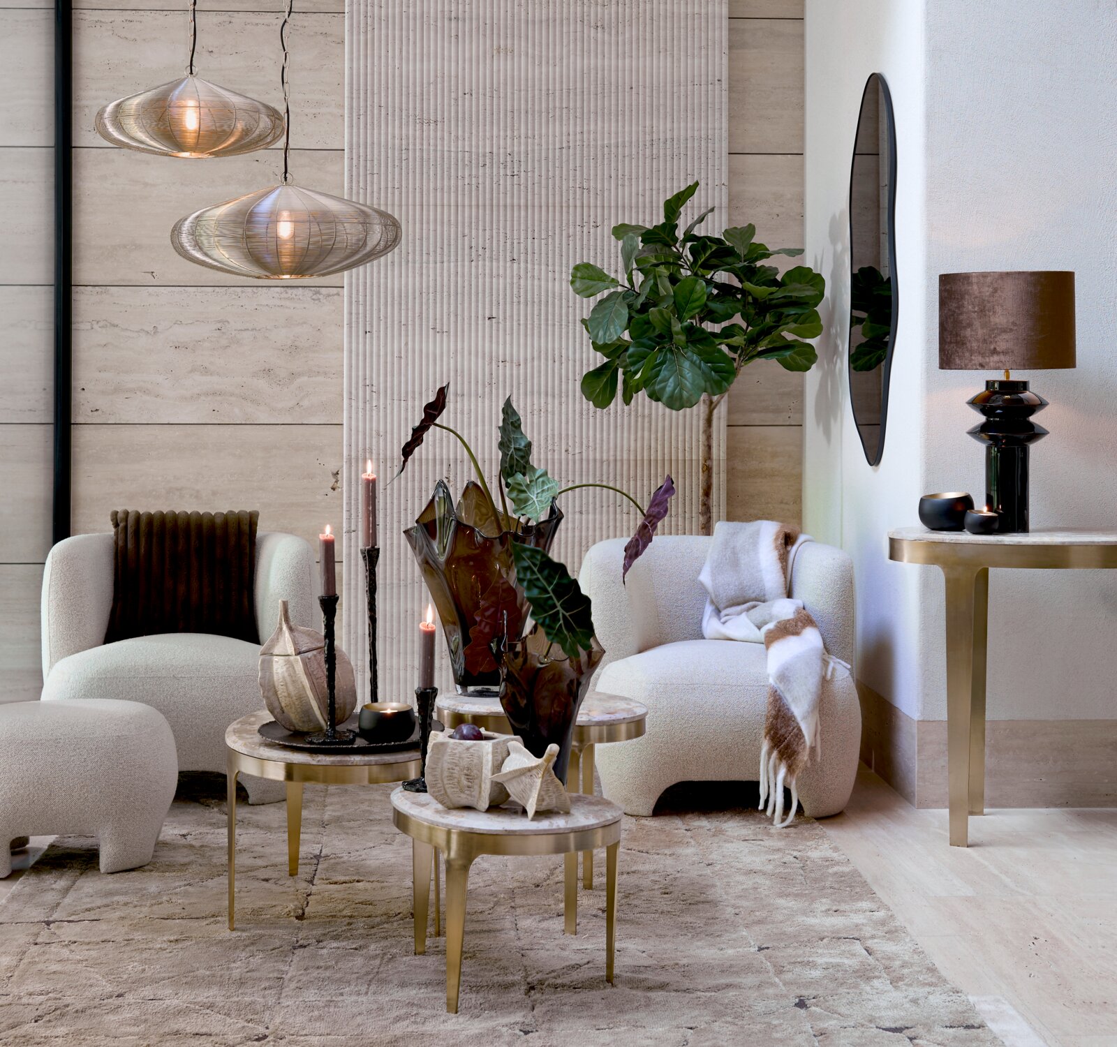 Frontalansicht eines stilvoll eingerichteten Wohnbereichs mit cremefarbenen Lounge-Sesseln, eleganten Messing-Couchtischen, skulpturalen Pendelleuchten und üppigen Grünpflanzen.