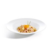 Tagliatelle Carbonara mit Speck, cremiger Sauce und rohem Eigelb, garniert mit Schnittlauch, auf weißem Teller vor hellem Hintergrund, Seitenansicht leicht von oben