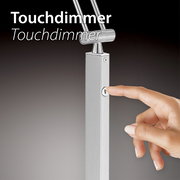 Nahaufnahme einer Hand, die den Touchdimmer einer silbernen Pendelleuchte betätigt.