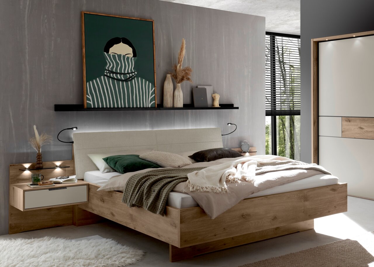 Modernes Schlafzimmer mit Holz-Doppelbett und gepolstertem Kopfteil, Nachttisch und Wandregal mit Dekoration; Aufnahme aus leicht schräger Frontperspektive.