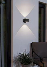 Moderne Wandleuchte 'TREVIOLO' in schwarzem Design, montiert an einer Außenwand, mit elegantem Lichtmuster. Seitliche Perspektive.