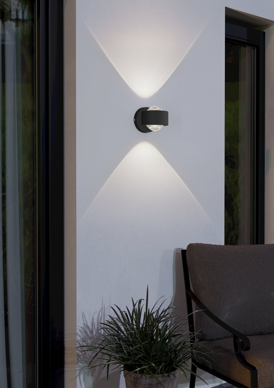Moderne Wandleuchte 'TREVIOLO' in schwarzem Design, montiert an einer Außenwand, mit elegantem Lichtmuster. Seitliche Perspektive.