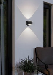 Moderne Wandleuchte 'TREVIOLO' in schwarzem Design, montiert an einer Außenwand, mit elegantem Lichtmuster. Seitliche Perspektive.