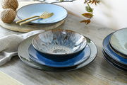Kombiservice Bali 16-tlg. in einer stilvollen Tischdekoration, seitliche Perspektive auf Teller und Schalen in verschiedenen Blautönen.