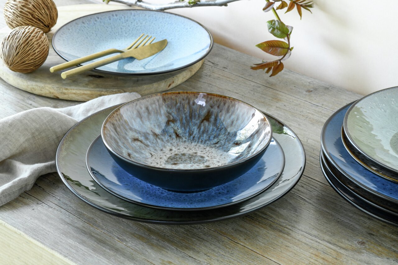 Kombiservice Bali 16-tlg. in einer stilvollen Tischdekoration, seitliche Perspektive auf Teller und Schalen in verschiedenen Blautönen.