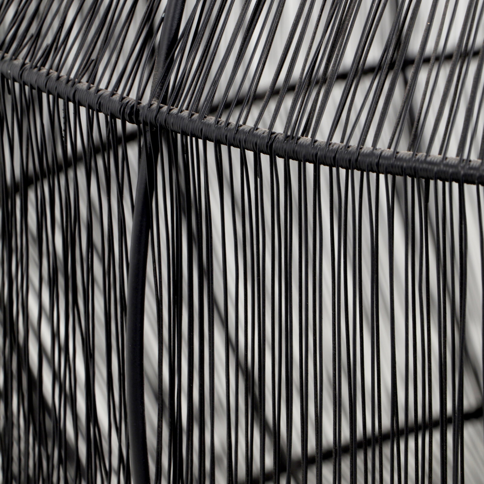 Nahaufnahme eines Beistelltisches mit schwarzem Drahtgestell, seitliche Perspektive