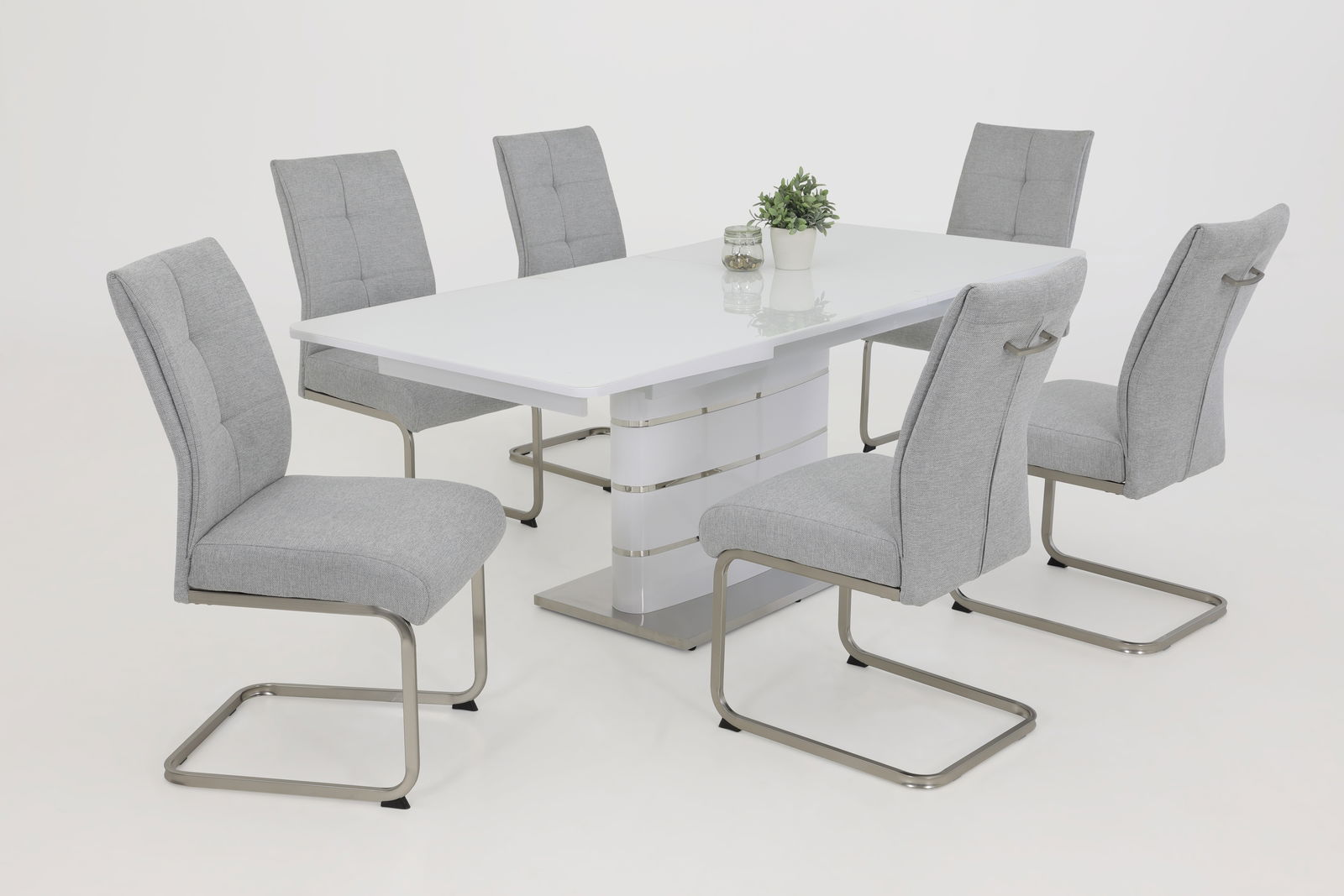 Sechs graue Schwingstühle um einen weißen Tisch, seitliche Perspektive