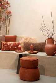 Braunes Kissen 60x30 cm LINA auf einer Bank, umgeben von weiteren Kissen und Dekorationen in warmen Erdtönen, seitliche Perspektive.