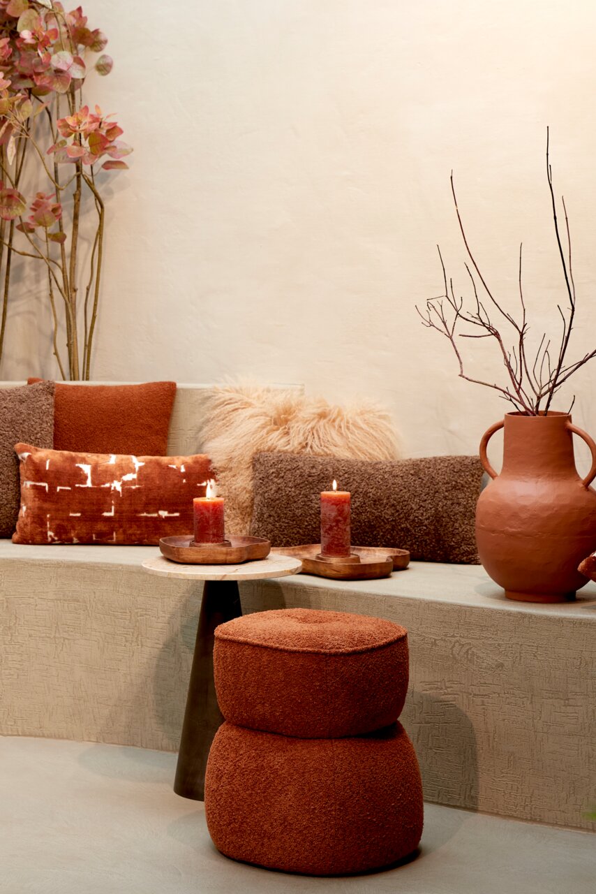 Braunes Kissen 60x30 cm LINA auf einer Bank, umgeben von weiteren Kissen und Dekorationen in warmen Erdtönen, seitliche Perspektive.