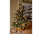 Weihnachtsbaum mit goldenen, grünen und weißen Kugeln, geschmückt in einem gemütlichen Wohnzimmer, seitliche Perspektive.