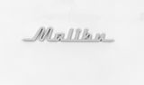 Nahaufnahme des Schriftzugs 'Malibu' auf einem weißen Hintergrund, perspektivisch von vorne.