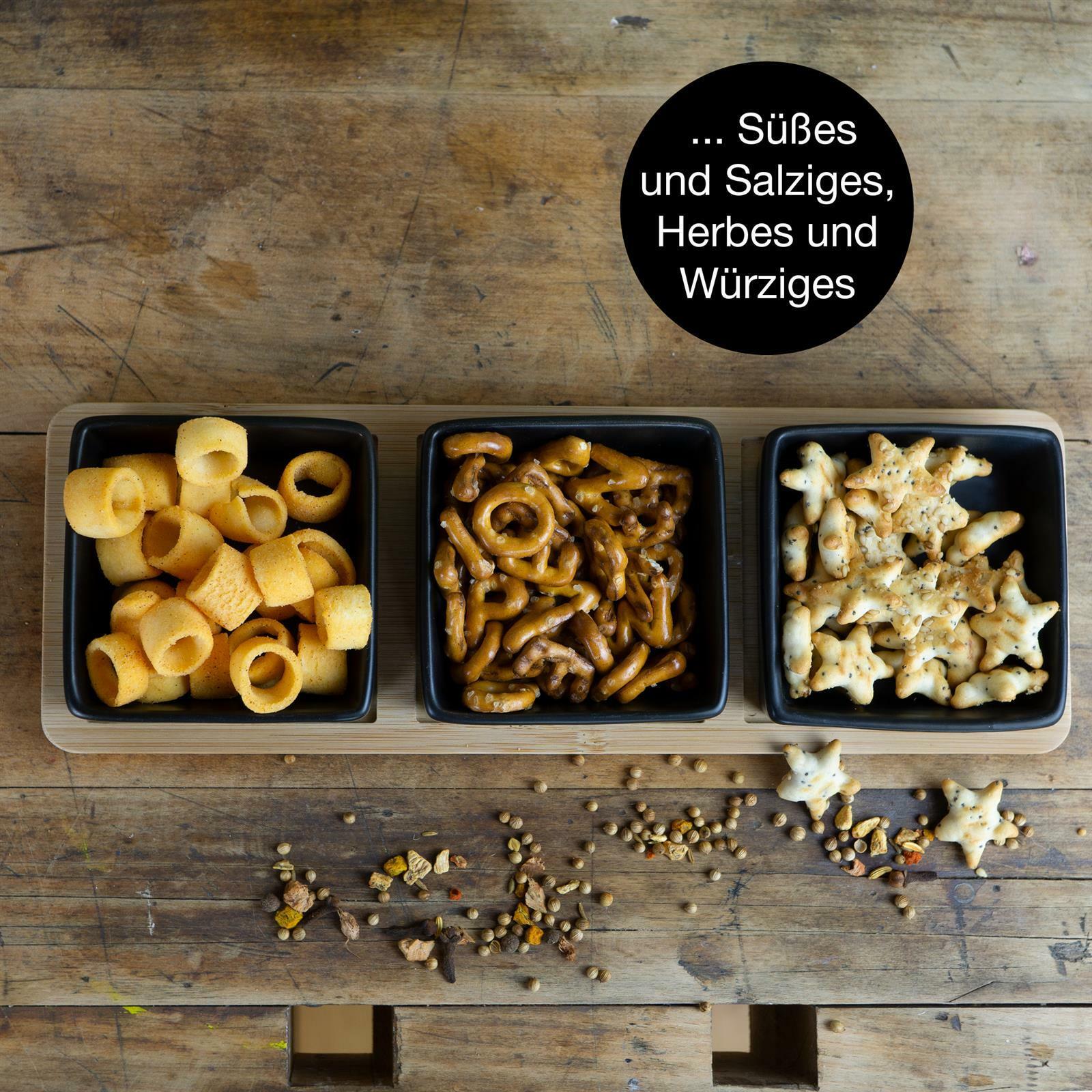 Servierset aus Bambus mit drei schwarzen Schalen, gefüllt mit verschiedenen Snacks, aus der Vogelperspektive fotografiert.