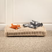 Hundematte aus weichem Material mit einem Spielzeugfuchs und einer grauen Decke mit Knochenmuster, seitliche Perspektive.