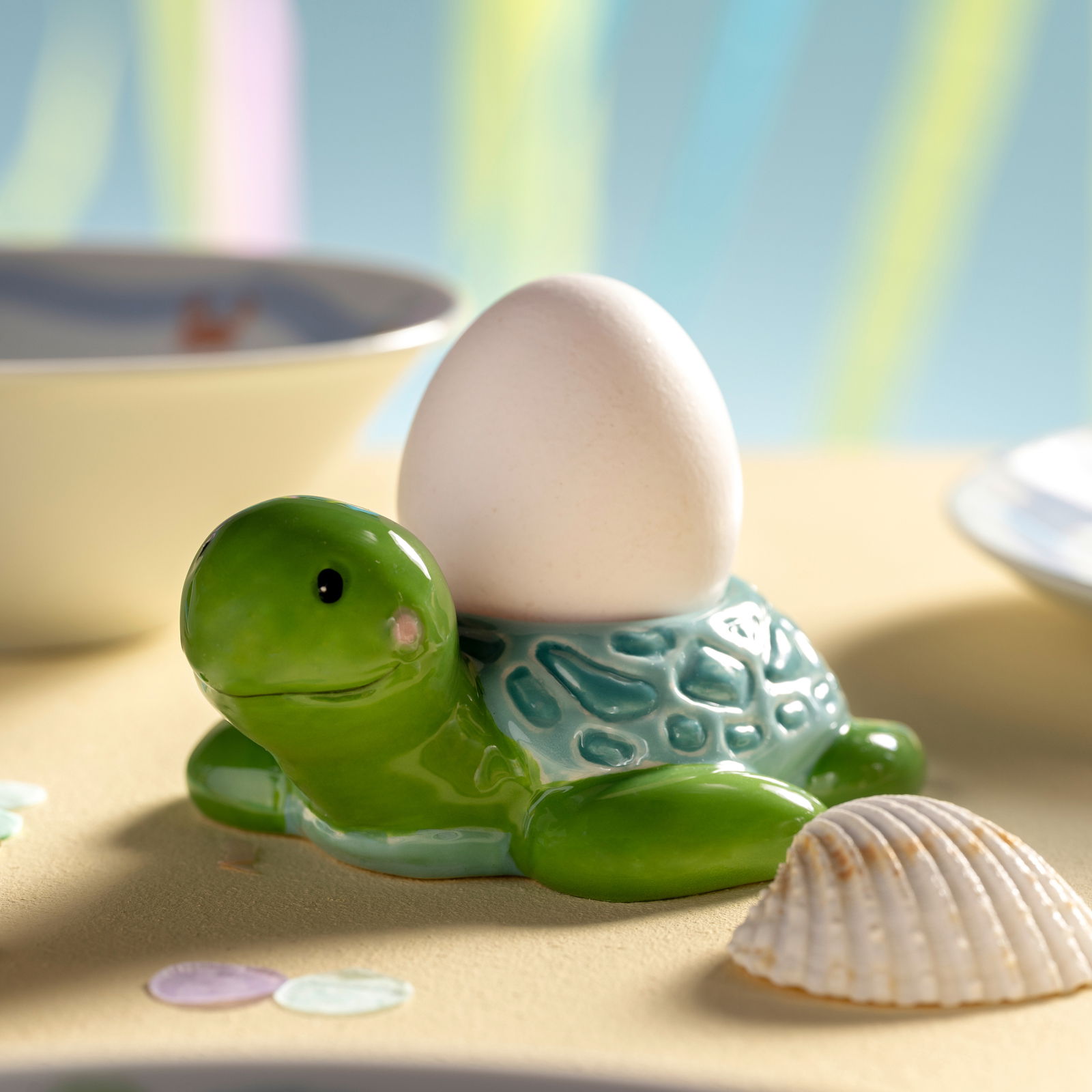 Eierbecher in Form einer grünen Schildkröte mit einem Ei auf dem Rücken, seitliche Perspektive