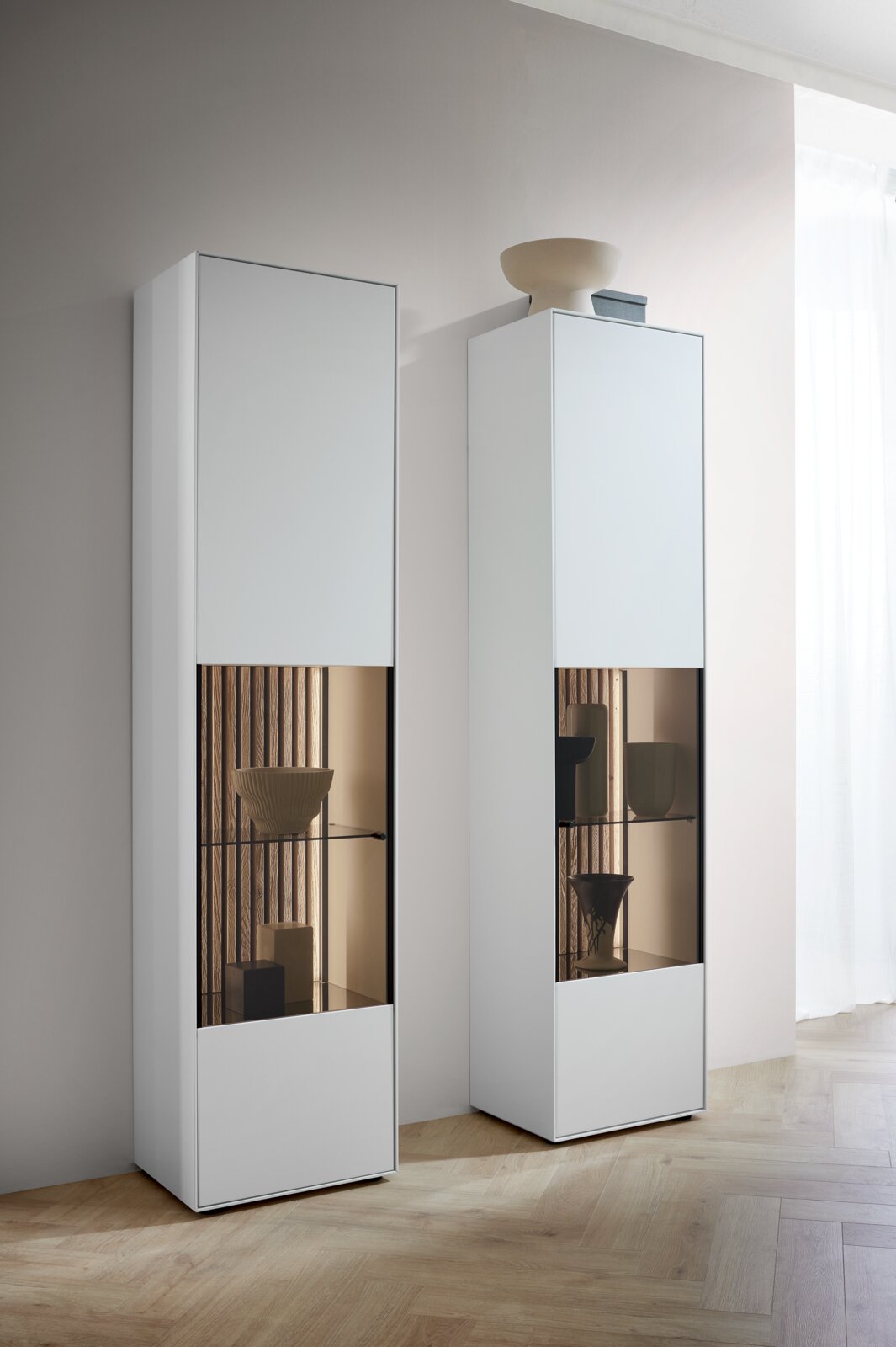 Moderne weiße Vitrine mit Glaseinsatz, linke Perspektive, dekoriert mit Keramikobjekten.