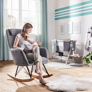 Stillstuhl in einem gemütlichen Raum, seitliche Perspektive, mit einer Frau, die ein Baby hält.