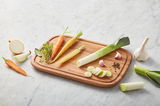 Holzschneidebrett mit frischem Gemüse wie Karotten, Lauch und Knoblauch, aus der Vogelperspektive fotografiert.