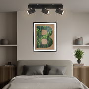 LED-Spot mit drei verstellbaren Strahlern, montiert an der Decke über einem Bett, aus der Perspektive des Bettes betrachtet.