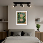 LED-Spot mit drei verstellbaren Strahlern, montiert an der Decke über einem Bett, aus der Perspektive des Bettes betrachtet.