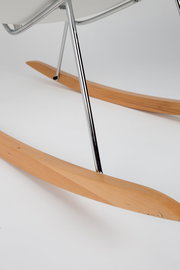 Nahaufnahme eines Schaukelsessels mit Holz-Kufen und Metallgestell, seitliche Perspektive.