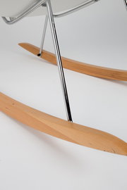 Nahaufnahme eines Schaukelsessels mit Holz-Kufen und Metallgestell, seitliche Perspektive.