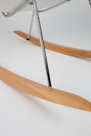 Close-up van een schommelstoel met houten glijders en een metalen frame, gezien vanaf de zijkant.