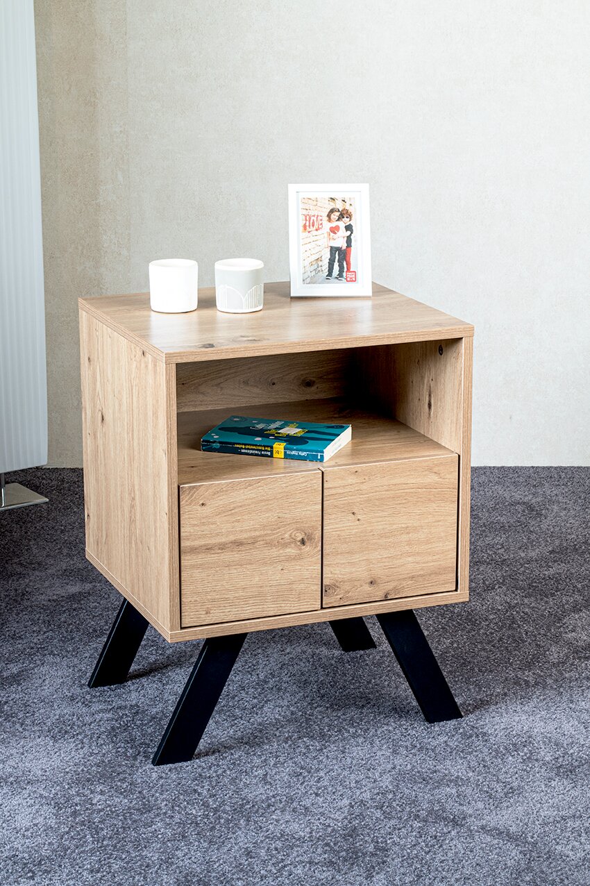 Holz-Nachttisch/Beistelltisch im Eiche-Look mit offenem Fach und zwei Türen auf schwarzen, schrägen Metallbeinen; Ansicht schräg von vorne.