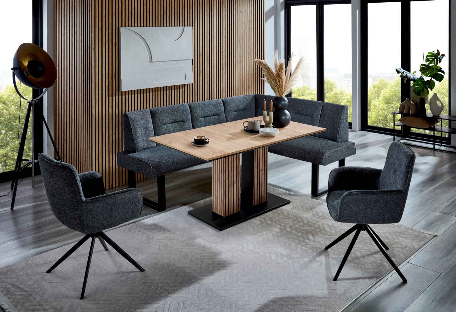 Valdera Eckbank KIRA Moderne Eckbankgruppe in einem stilvollen Wohnzimmer mit Holzvertäfelung und großen Fenstern, aus der Perspektive von vorne.