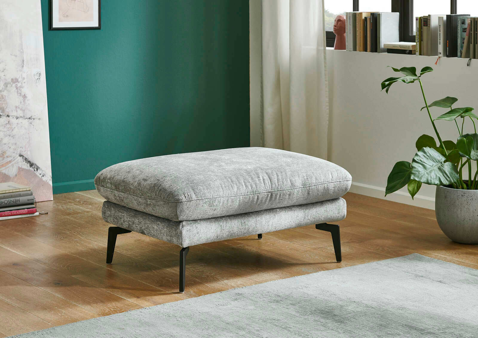 Beldomo System XL-Hocker AUGSBURG Grauer XL-Hocker mit schwarzen Beinen, seitliche Perspektive, in modernem Wohnzimmer mit Holzboden und grüner Wand.