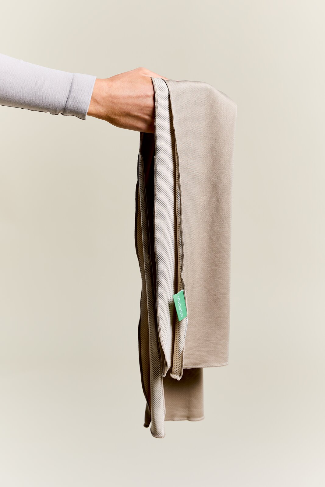 Beige sporthanddoek die door één hand wordt vastgehouden, zijaanzicht