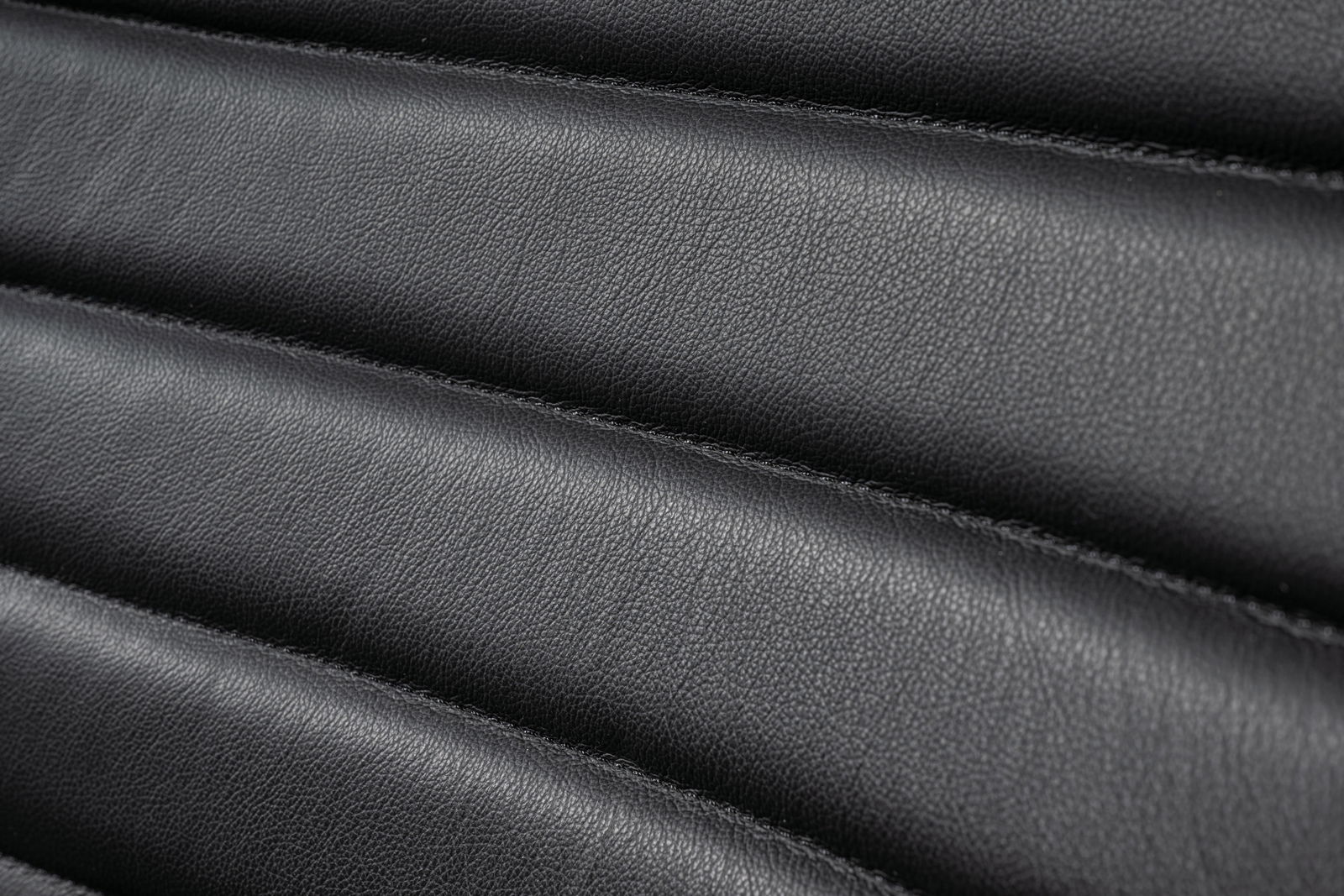 Nahaufnahme der schwarzen Lederpolsterung eines Schwingstuhls in horizontaler Perspektive