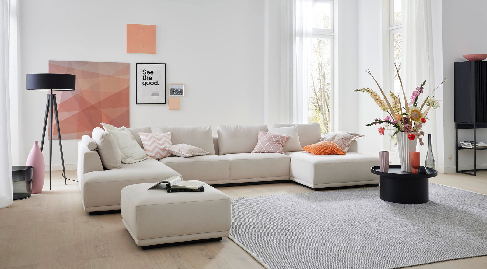Modernes Ecksofa in hellem Beige mit Kissen in verschiedenen Farben, umgeben von stilvoller Dekoration in einem hellen Wohnzimmer. Perspektive von vorne.